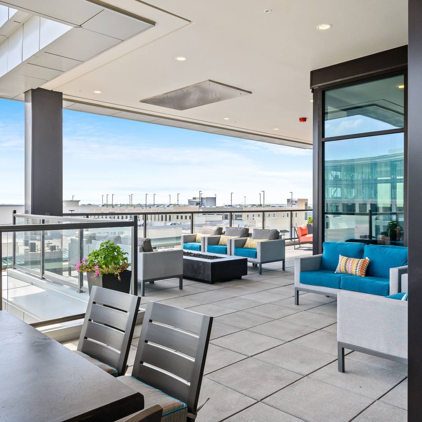 The District Flats apartment outdoor lounge on 5th floor with tables, chairs, and fire pits looking out over city view of Lenexa, KS