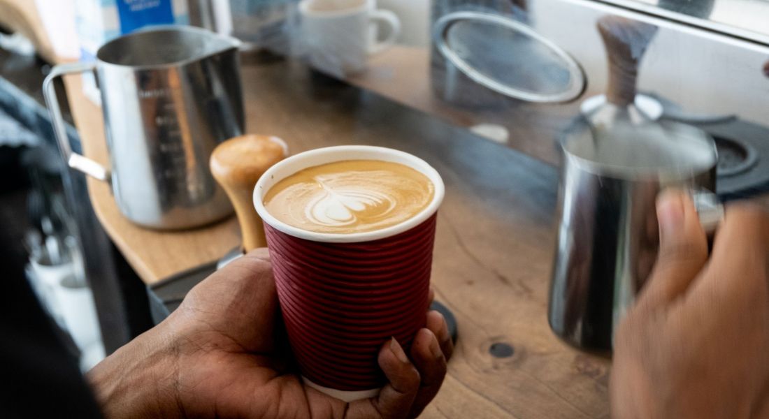 Close up of barista making a delicious golden flat white coffee in local coffee shop