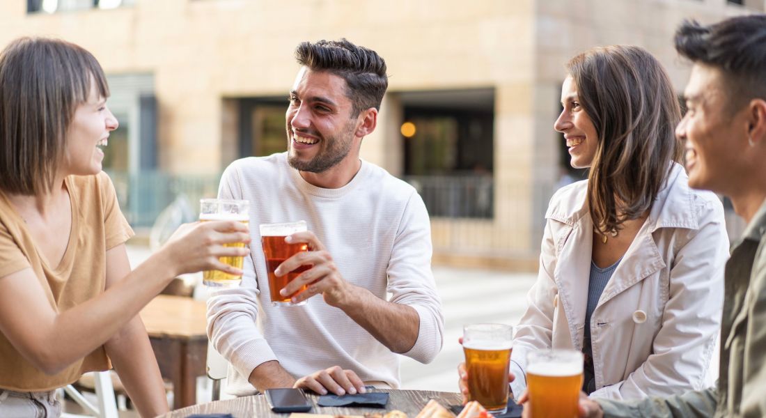 Happy friends drinking beer at the outdoor pub in the city